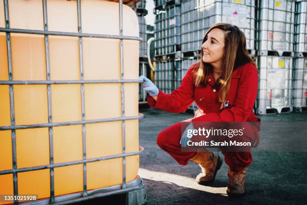 woman in red overalls next to vat of cleaning fluid - red jumpsuit stock pictures, royalty-free photos & images