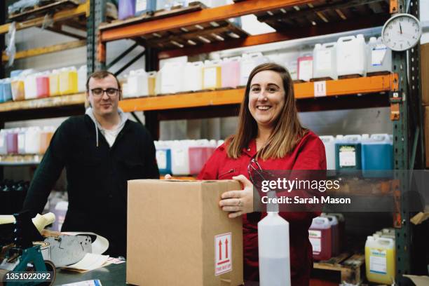 workers packing boxes in factory - red jumpsuit stock pictures, royalty-free photos & images