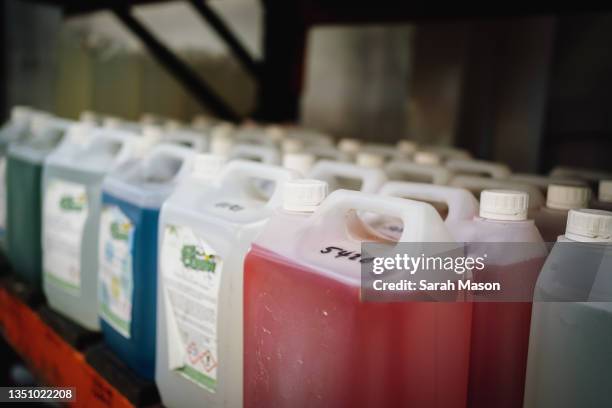 big plastic containers of different colour cleaning fluids - producto de limpieza fotografías e imágenes de stock