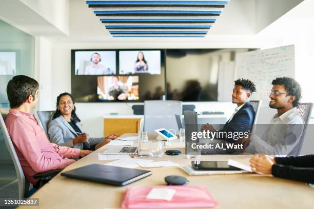 smiling young businesspeople talking during a video conference call in a boardroom - meeting room screen stock pictures, royalty-free photos & images