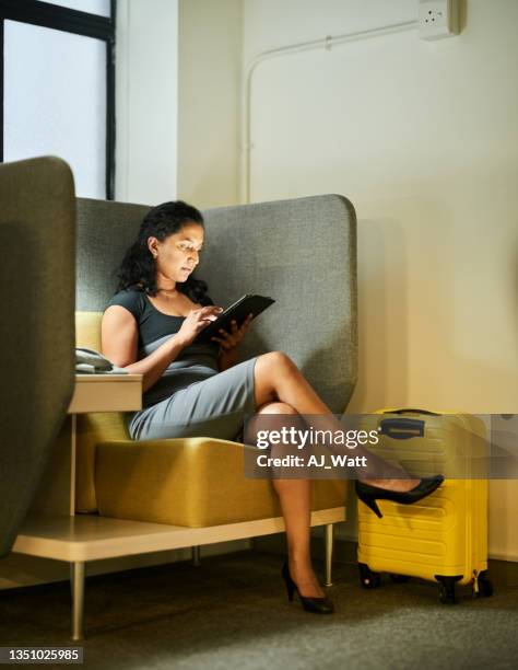 young female passenger using digital tablet at airport lounge - gate stockfoto's en -beelden