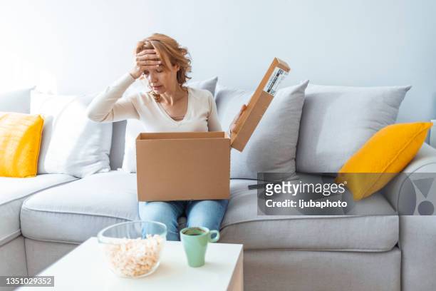 woman unpacking wrong parcel, delivery mistake - damaged parcel stock pictures, royalty-free photos & images