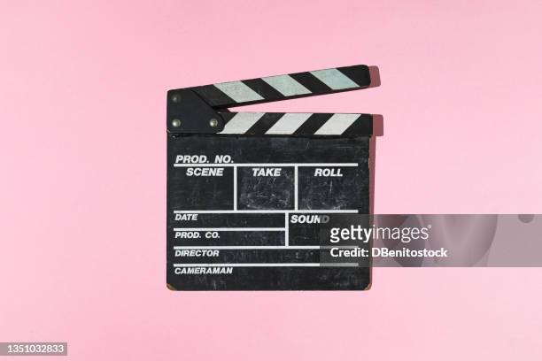 old wooden movie clapperboard with hard shadow on pink background. concept of film industry, cinema, entertainment, and hollywood. - カチンコ ストックフォトと画像