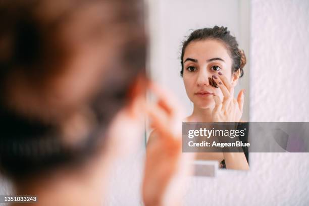 young woman doing skin mask in front of mirror - esfoliação imagens e fotografias de stock