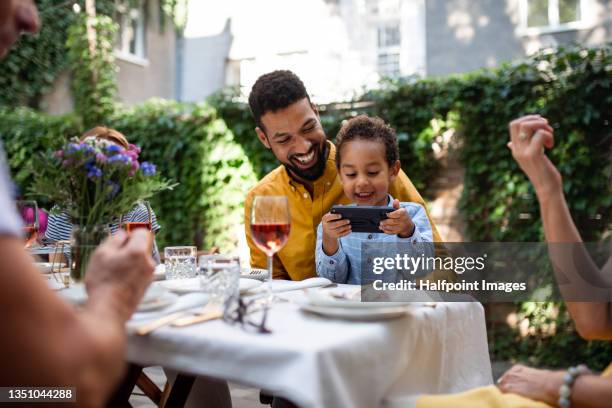 portrait of multiracial three generations family having dinner together outdoors in front or back yard. - alpha stock pictures, royalty-free photos & images