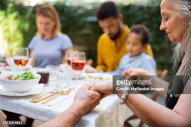 portrait of multiracial three generations family praying together when dining outdoors in front or back yard. - religion bildbanksfoton och bilder