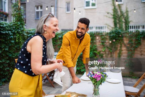 young man with his mother in law setting table for family dinner outdoors in garden. - sogra imagens e fotografias de stock