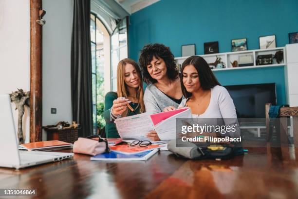 a mother is helping her daughter and a friend with the homework - university student support stock pictures, royalty-free photos & images