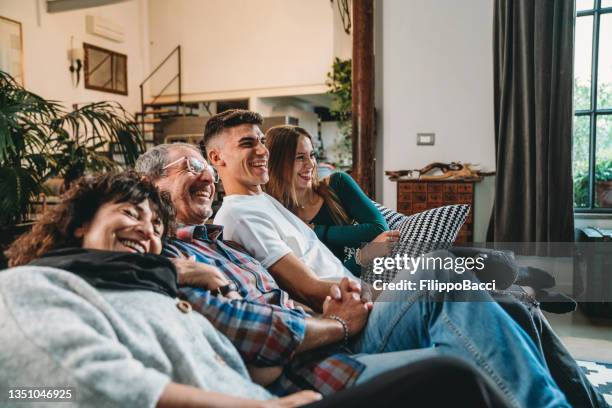 familie mit zwei heranwachsenden kindern schaut zu hause auf dem sofa fern - men women & children film stock-fotos und bilder