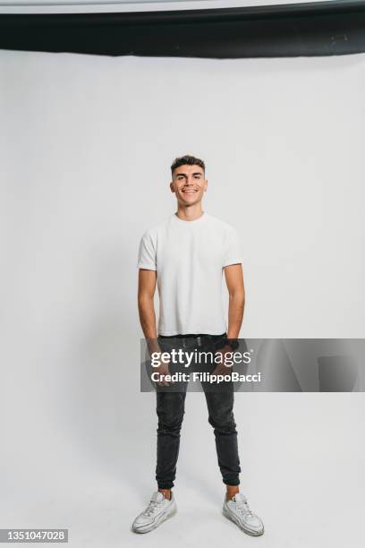 portrait of a young adult man against a photographic background in a studio - man white background stock pictures, royalty-free photos & images