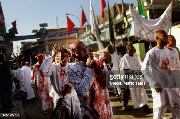 Shi'ite worshipers march after cutting their scalps in a ritual display of mourning during an Ashura commemoration ceremony outside Kadhimiya shrine...