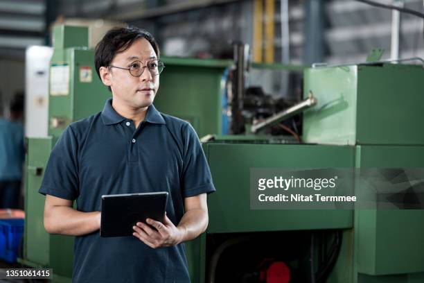 improved valuation and costing capabilities in the manufacturing industry. shot of a factory owner working on a digital tablet at the cnc milling machine in the engineering part production line. - midsection 個照片及圖片檔