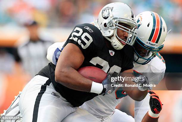 Running back Michael Bush of the Oakland Raiders is tackled by linebacker Kevin Burnett the Miami Dolphins during a NFL game at Sun Life Stadium on...