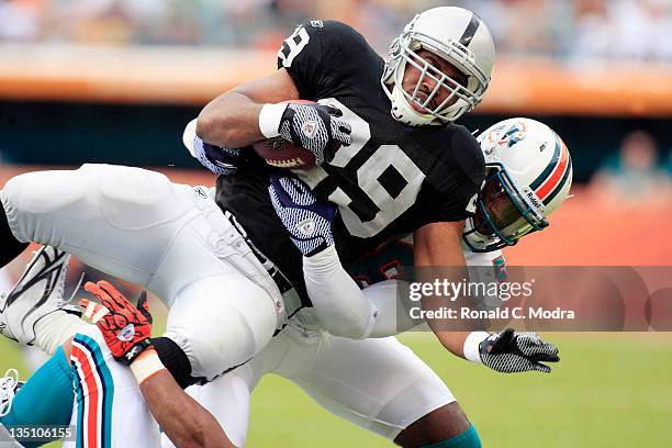 Running back Michael Bush of the Oakland Raiders is tackled by linebacker Kevin Burnett the Miami Dolphins during a NFL game at Sun Life Stadium on...