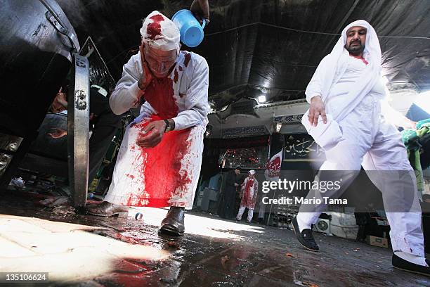 Shi'ite worshiper washes himself after cutting his scalp in a ritual display of mourning during an Ashura commemoration ceremony outside Kadhimiya...