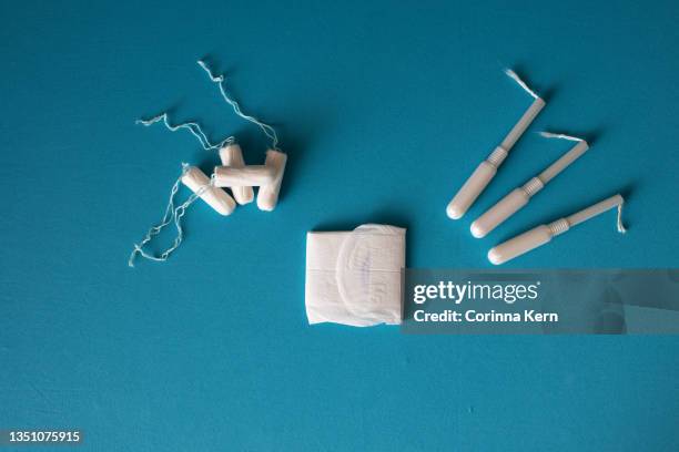 arrangement of tampons and sanitary pad on blue background - tampon stock pictures, royalty-free photos & images