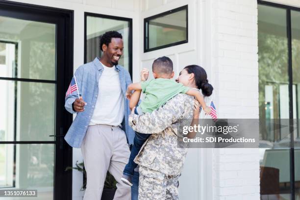 family carrying american flags are happy to see soldier mom - military home stock pictures, royalty-free photos & images