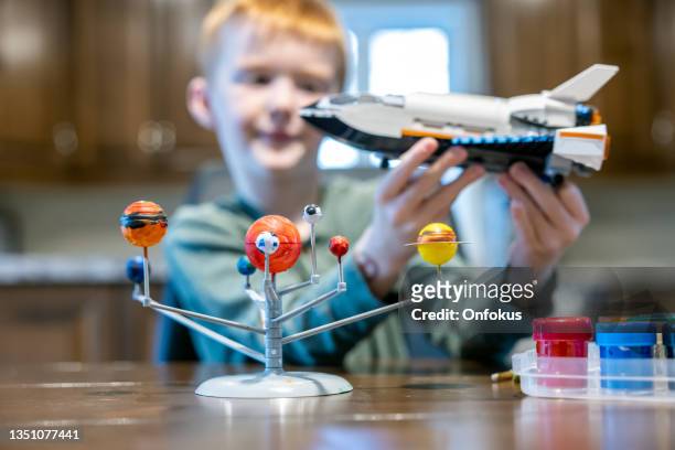 cute redhead boy playing with homemade solar system and rocket or spaceship - toy rocket stock pictures, royalty-free photos & images