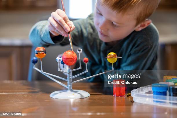 cute redhead boy creating his homemade solar system and painting planets - pluto dwarf planet stockfoto's en -beelden
