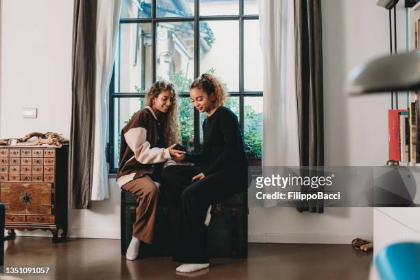 two young adult friends sitting near a big window at home - moroccan girls bildbanksfoton och bilder