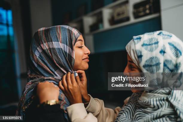two young adult friends are fixing their hijab at the mirror - moroccan girls stock pictures, royalty-free photos & images