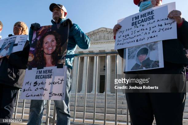 People hold signs and pictures of family members killed in shootings during a demonstration by victims of gun violence in front of the Supreme Court...