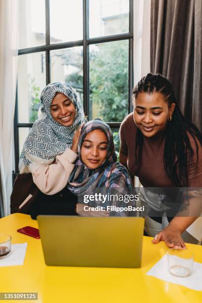 three friends are making a video call with a laptop at home - religious role stock pictures, royalty-free photos & images