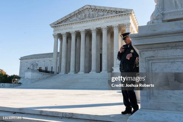 Police officer maintains a watch during a demonstration by victims of gun violence in front of the Supreme Court as arguments begin in a major case...