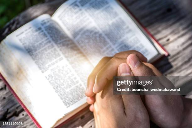 human hand placed on the bible, pray to god. - jesus is alive stock-fotos und bilder