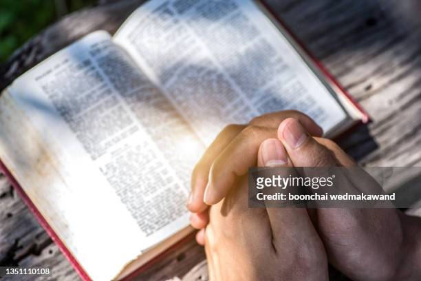 human hand placed on the bible, pray to god. - resurrection religion fotografías e imágenes de stock