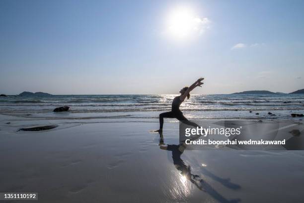 young woman on the beach and practicing yoga - yogi stock pictures, royalty-free photos & images