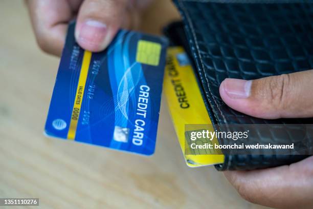 cropped image of businessman giving credit card from wallet at desk - männliche figur stock-fotos und bilder