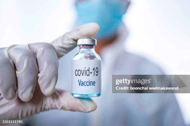 doctor, nurse, scientist, researcher hand in blue gloves holding flu, measles, coronavirus, covid-19 vaccine disease preparing for human clinical trials vaccination shot, medicine and drug concept. - measles hand stock pictures, royalty-free photos & images