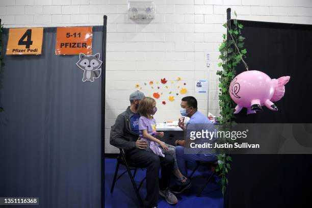 Ian Chipman holds his 7-year-old daughter Lilah Chipman as Dominic Dinh prepares to administer a pediatric Pfizer COVID-19 vaccination during a...