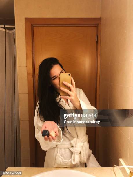 woman taking a selfie in the bathroom while holding two bars of soap - mirror selfie - fotografias e filmes do acervo