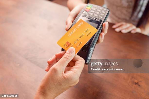 person paying with a credit card using a credit card terminal - credit card stock-fotos und bilder