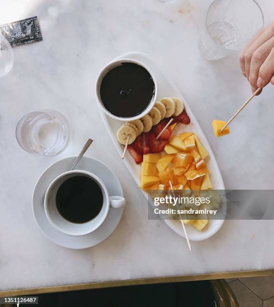 overhead view of a person eating a chocolate fruit fondue with a cup of coffee - chokladfondue bildbanksfoton och bilder