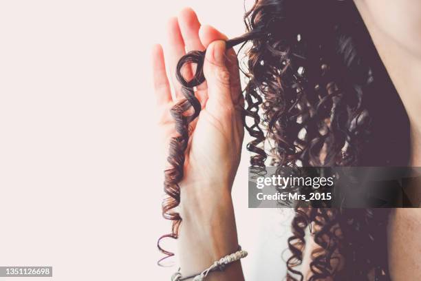 close-up of a woman holding her corkscrew curled hair - hair curls photos et images de collection