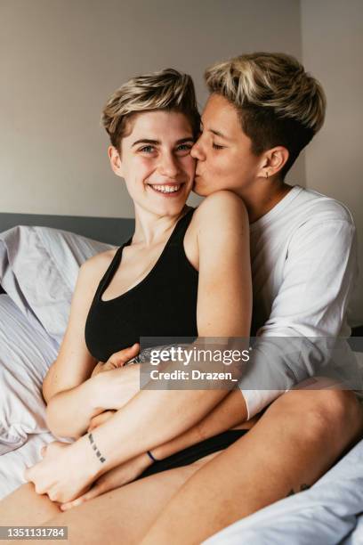 lesbian couple at home, waking up together in bed and kissing - photos of lesbians kissing stock pictures, royalty-free photos & images