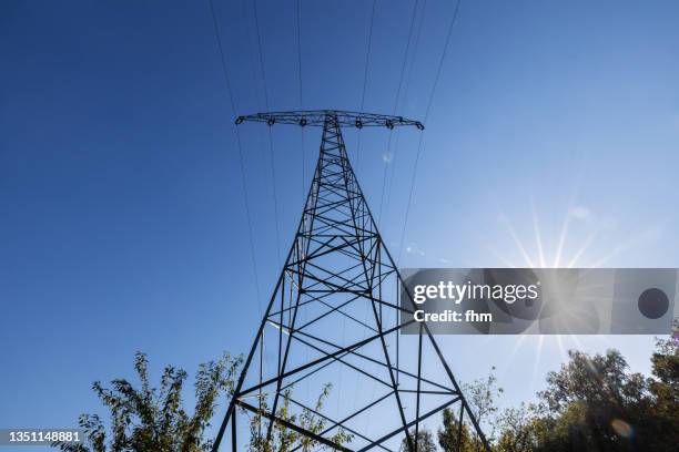 electricity pylon with bright sun - blackout picture stock-fotos und bilder