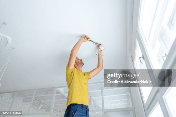 electrician fixing ceiling lights - installing ceiling light fixture stock pictures, royalty-free photos & images
