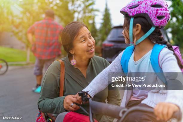 mom helping daughter get ready to ride bike to school - native american family stock pictures, royalty-free photos & images