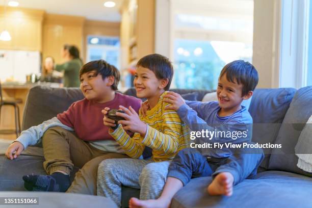 happy elementary age boys playing video games together at home - native american family stock pictures, royalty-free photos & images