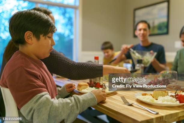 multi-ethnic group of family and friends eating together at holiday table - indian family dinner table stock pictures, royalty-free photos & images