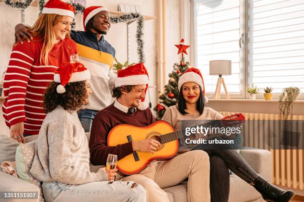 friends celebrate christmas playing guitar and singing - acoustic christmas stock pictures, royalty-free photos & images