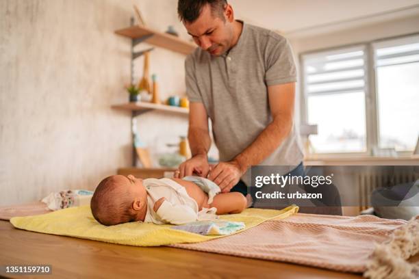 father changing his infant baby diaper - adult diaper stockfoto's en -beelden