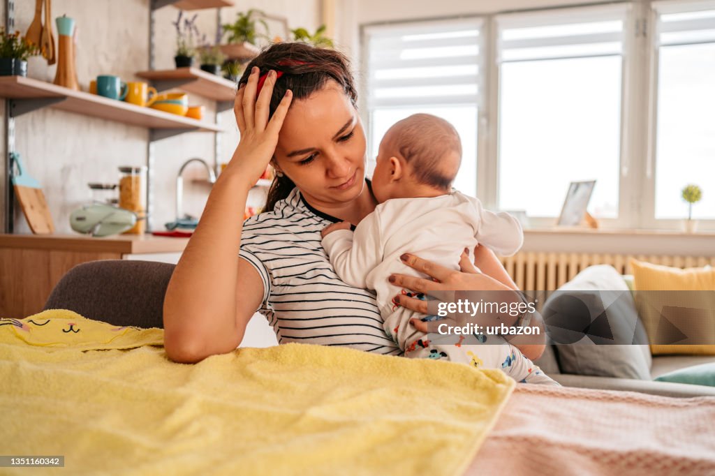 Mutter hält ihr neugeborenes Baby und fühlt sich schläfrig