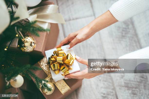 tender woman hands putting gift box under the christmas tree - christmas presents under tree stock pictures, royalty-free photos & images