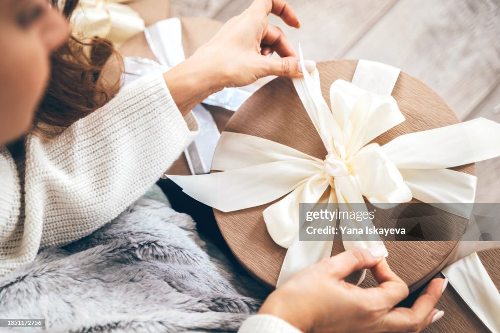 Close-up of a woman wrapping gifts and tying a beautiful pastel ribbon bow