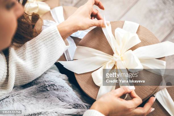 close-up of a woman wrapping gifts and tying a beautiful pastel ribbon bow - wrapping - fotografias e filmes do acervo